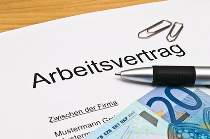 Das Bild zeigt einen Arbeitsvertrag mit Kugelschreiber und Geld